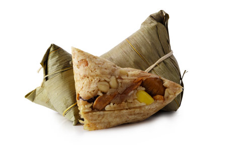 Zongzi or Bacang is a sticky rice dumpling wrapped in bamboo leaves, filled with savory or sweet ingredients, enjoyed during the Dragon Boat Festival. isolated on a white backgroundの写真素材