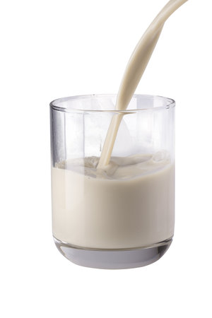Fresh Milk Being Poured into a Clear Glass isolated on a white backgroundの写真素材