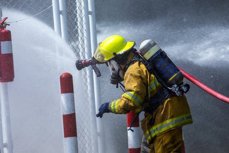 Firefighters in Action Spraying Water to Stop the Fireの写真素材