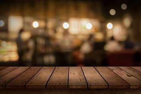 Wood table top on blur bokeh coffee shop or cafe restaurant background. Can be used for display or montage your products.の写真素材