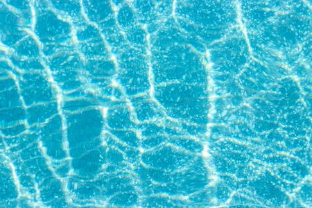 Abstract top view blue ripple swimming pool water and sun reflection caustics.