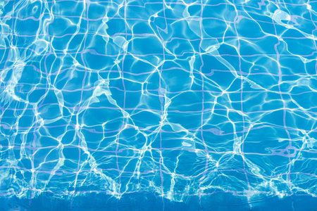Blue swimming pool water surface and ripple wave background. Summer abstract reflection caustics in swimming pool.の写真素材