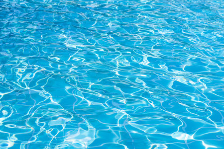 Blue swimming pool water surface and ripple wave background. Summer abstract reflection caustics in swimming pool.の写真素材