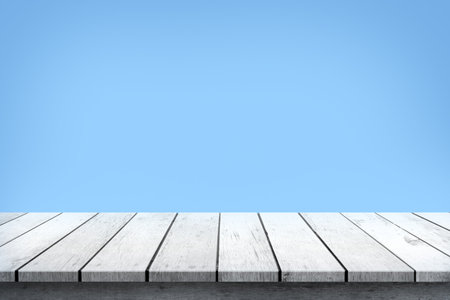 Empty white wooden table top on blue background, used for display or montage your products.の写真素材