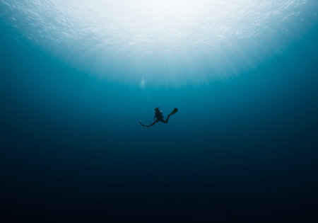 Silhouette of a scuba diver swimming in the blue ocean
