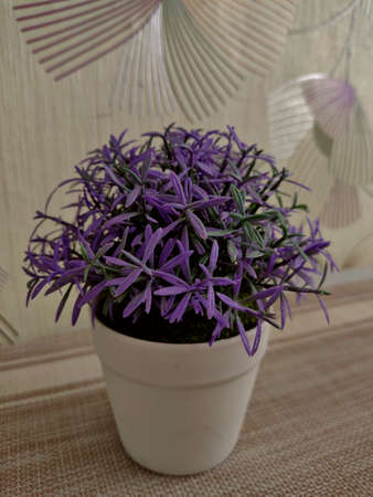 Plastic pot with artificial purple flower.の写真素材