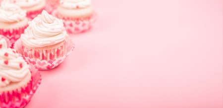Valentine day love cupcakes decorated with cream and hearts on pink background with copy space for textの写真素材