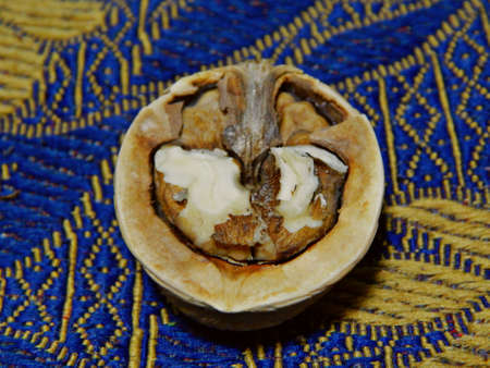 Half of a walnut on a blue canvas with golden leaves. Close up of a walnut.