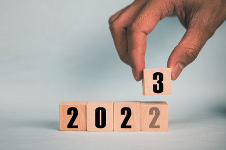 Hand hold wooden cubes 2023 and 2023 concept business change to new success