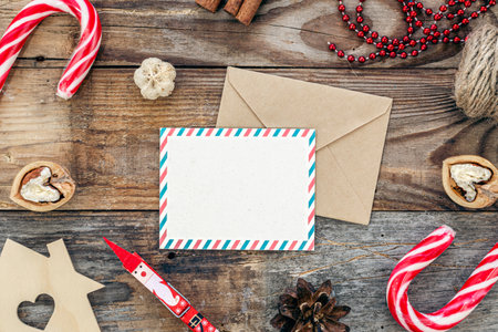 Blank paper, envelope and cozy Christmas decor details on wooden background, flat lay.の写真素材