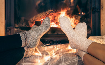 Women's feet in warm socks are heated by the home fireplace with a bright flame.の写真素材