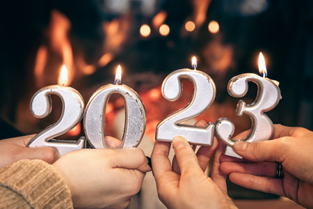 Burning candles in the form of numbers 2023 in female hands, the concept of the new year and...