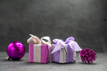 top view giftboxes pink and purple with ribbons pink xmas tree toys on dark isolated background free spaceの写真素材