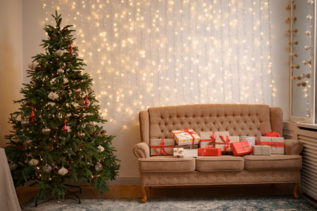 Festive interior with many presents on comfortable sofa and decorated Christmas treeの写真素材