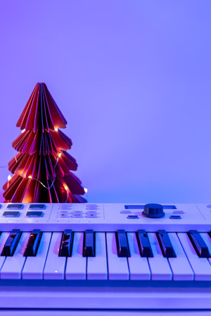 Minimalistic Christmas background with midi keyboard and paper tree with neon lighting, copy space.の写真素材