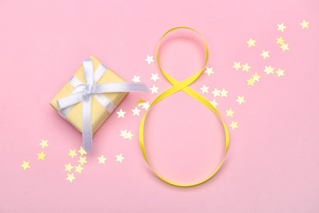 Figure 8 made of ribbon, gift box and confetti on color background. International Women's Day celebrationの写真素材