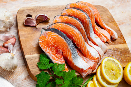 Image of raw salmon steaks with lemon and greens before cooking..の写真素材
