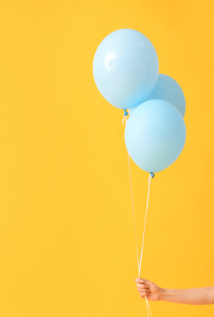 Human hand with air balloons on color backgroundの写真素材