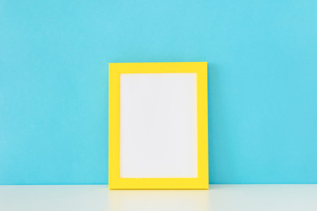 yellow empty photo frame front blue wallの写真素材