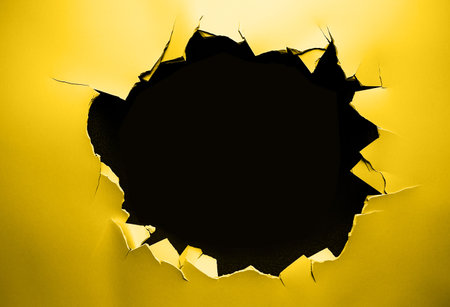 Yellow paper torn up with black hole middleの写真素材