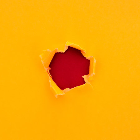 Torn yellow paper with space text red cardboard backgroundの写真素材