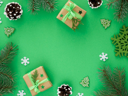 Christmas background with fir branches, cones, gift boxes and snowflakes on green backgroundの写真素材