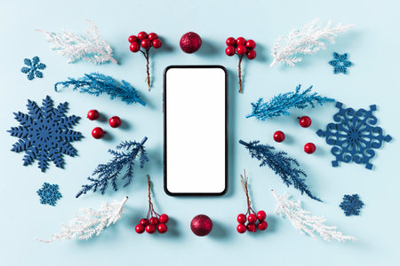 Mockup smartphone with blank screen and Christmas decorations on blue background