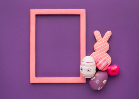 Easter eggs, bunny and frame on purple background. Top view