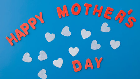 Happy Mother's Day text on blue background with white hearts. Top view.の写真素材