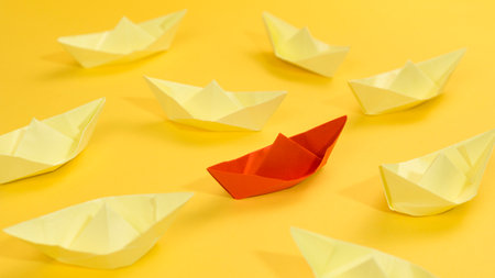Paper boats on a yellow background. The concept of leadership and success.の写真素材