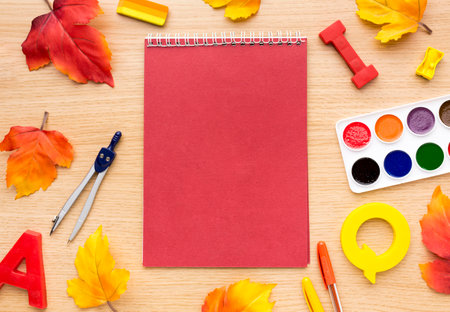 School supplies on a wooden background with autumn leaves. Back to school.