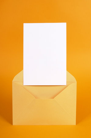 Metallic gold envelope with blank message card letter or invitation isolated on an orange background. Space for copy.の写真素材