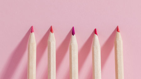 top view of row of wooden pencils on pink background with copy spaceの写真素材