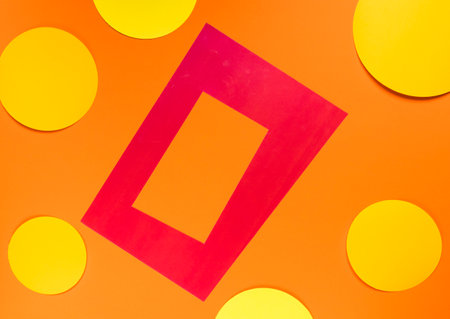Colorful paper photo frame on orange and yellow background, top view