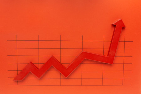 Red arrow graph on red paper background. Business and financial concept.