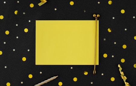 Blank yellow note paper on black background with yellow confetti.