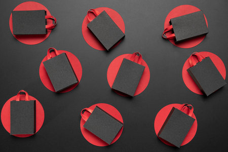 Black paper shopping bags on black background. Flat lay, top view.