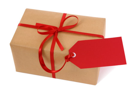 Brown paper package or gift tied with red ribbon and gift tag isolated on white backgroundの写真素材