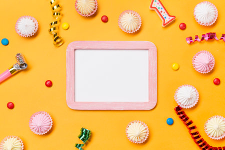 Birthday party background with sweets and blank photo frame. Flat lay, top view