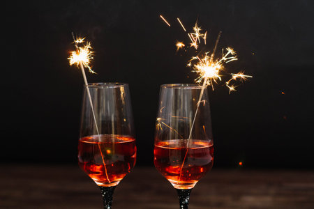 Two glasses of wine with sparklers on a black background, close-upの写真素材