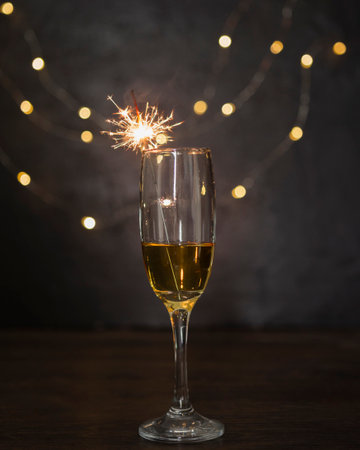 Champagne glass with sparkler and bokeh lights on backgroundの写真素材