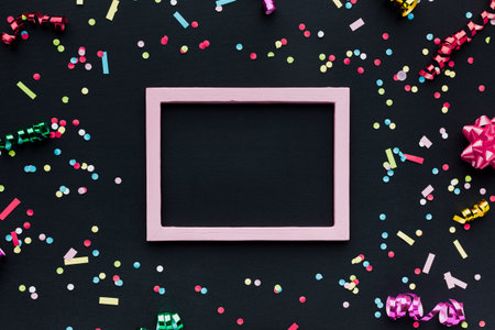 Colorful confetti and pink frame on black background, top viewの写真素材