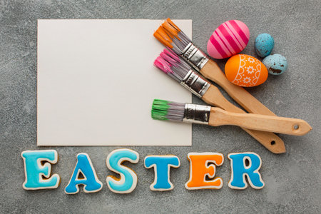 Colorful Easter eggs, paint brushes and lettering on grey background