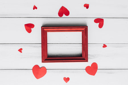 top view of red wooden frame and red hearts on white wooden backgroundの写真素材
