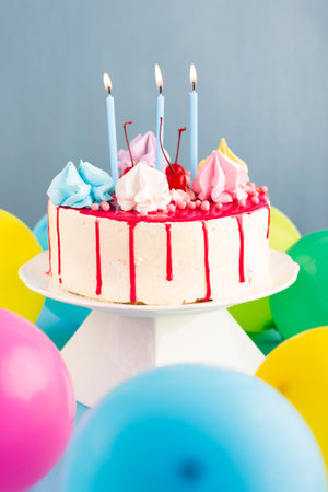 Birthday cake with candles and balloons on blue background, closeupの写真素材