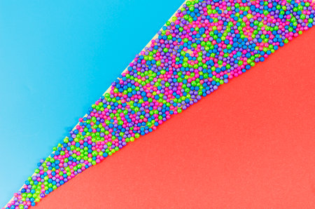 Colorful sugar sprinkles on blue and red background. Top view, copy space