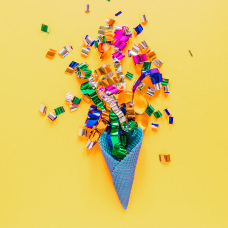Colorful confetti in a cone on a yellow backgroundの写真素材