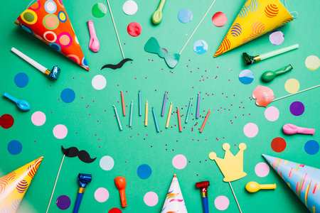 Birthday party items and confetti on green background with copy spaceの写真素材