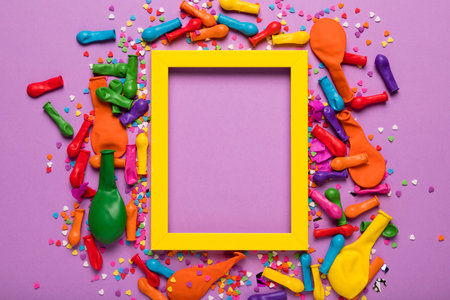 Frame with colorful balloons and confetti on color background, top viewの写真素材