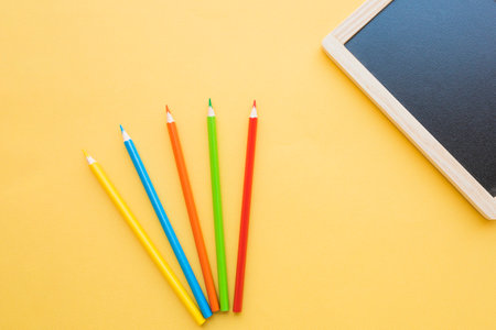 Colorful pencils and blackboard on yellow background. Back to school concept.の写真素材
